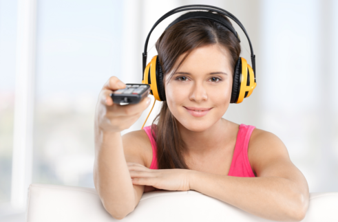 Girl wearing headphones, pointing a remote control with her right hand