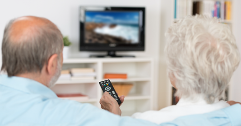 Elderly couple watching TV together. Woman pointing remote at screen. Image credit: Defining progress for Access Services on Video on Demand (VOD)