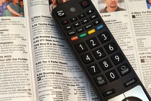 Remote control resting on a TV guide