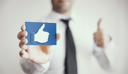 Man giving thumbs up whilst holding card with Facebook 'like' icon