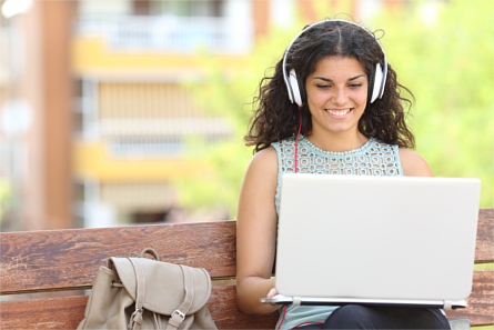 Woman using a laptop with headphones outdoors