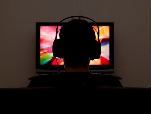 Man wearing headphones listens to AD on TV