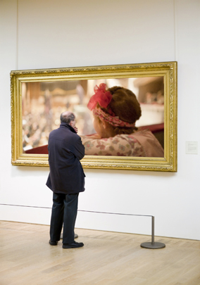 A man looking at a painting in an art gallery.