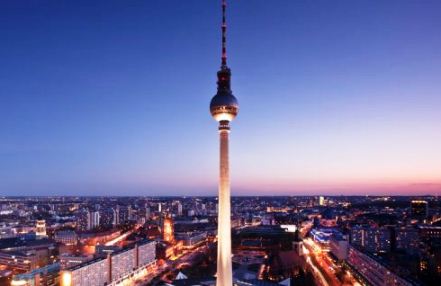 The Fernsehturm television tower with the city of Berlin in the background at sunset.
