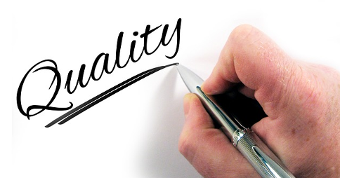 Man writing the word 'Quality' with ballpoint pen in right hand