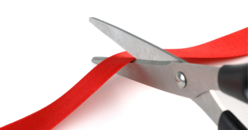 Scissors cutting through a red ribbon