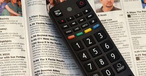 Television remote control resting on printed TV guide