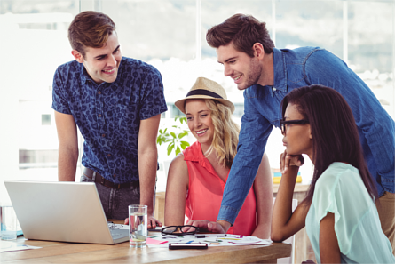 Team of young adults working around a laptop