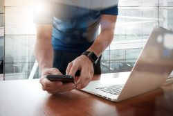 Man uses phone and laptop