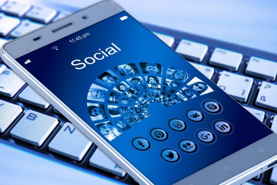 Mobile with social media icons on top of a keyboard